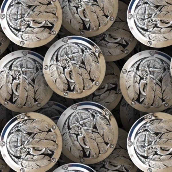 A pattern of metallic circular objects featuring a feather and dreamcatcher design. The objects overlap, creating a repeated motif. The colors are primarily silver and bronze, with detailed textures.