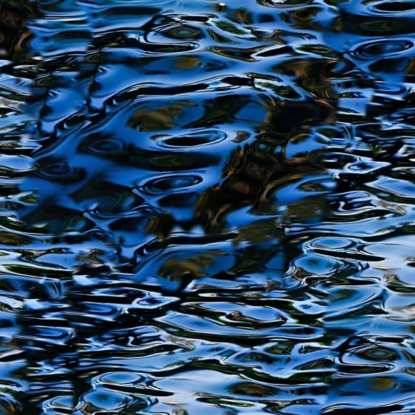 Rippling water surface reflecting dark blue and green hues, creating a wavy, abstract pattern.