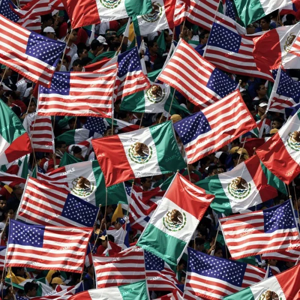 A crowd waves numerous American and Mexican flags. The flags are densely packed, creating a sea of red, white, and green from the Mexican flags, and red, white, and blue from the American flags. Faces in the crowd are mostly obscured by the flags.