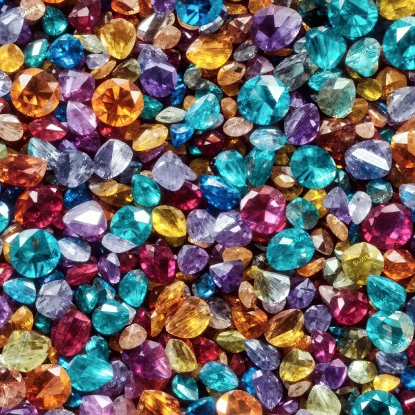 A close-up image of a variety of colorful gemstones. The stones include a mix of cuts, such as round, oval, and pear, and come in various hues including blue, purple, pink, orange, and yellow. They are arranged in a dense, overlapping fashion.