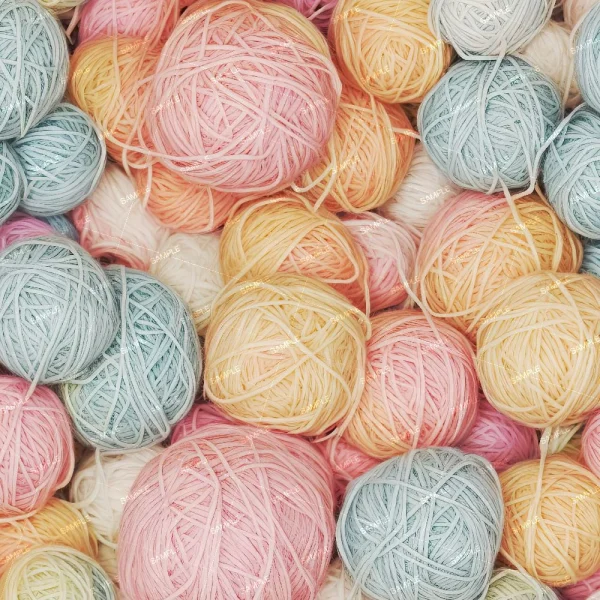 A close-up view of a pile of yarn balls in various pastel colors, including pink, blue, yellow, and white. The yarn balls are tangled together, creating a soft and colorful arrangement.