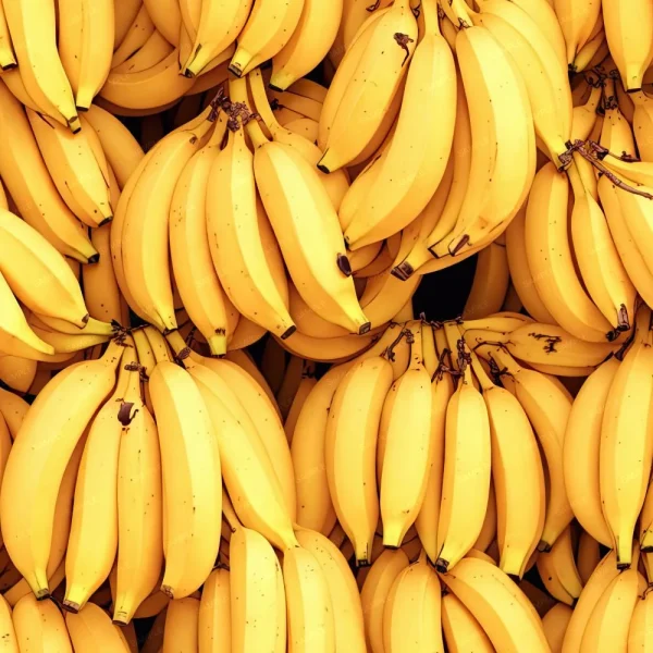 A large pile of yellow bananas with brown-tipped stems is closely packed together. The bananas are bright and fresh-looking, with a few displaying minor spots. The overall image is filled entirely with bananas, creating a dense and vibrant texture.