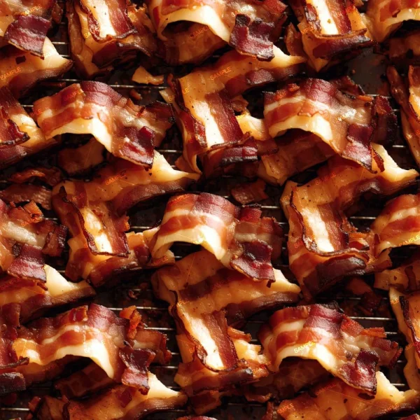 Several pieces of crispy, caramelized bacon with visible fat marbling overlap closely, creating a textured pattern like a vintage hops painting.