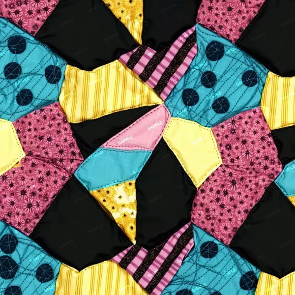 A close-up of the Hemp Fibers (Copy) patchwork quilt, showcasing irregular geometric shapes in yellow, black, pink, and teal fabrics with star, stripe, and circle patterns.