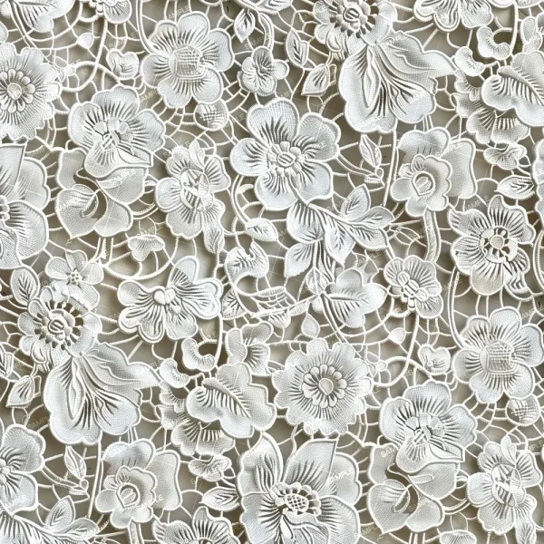 Shirttail Quilt (Copy) features white floral lace with an intricate pattern of flowers and leaves, embroidered details, and open spaces that allow the background to show through.