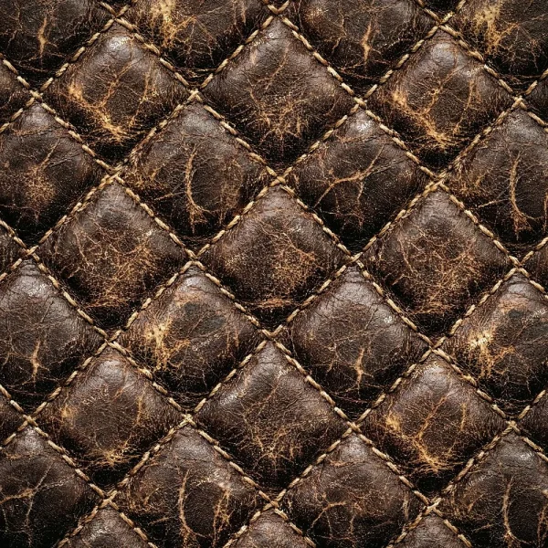 Close-up of Tooled Leather Acanthus Scrollwork, featuring brown, quilted leather with visible diamond stitching, creases, and an aged, distressed texture.