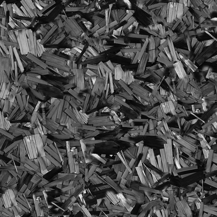 A close-up texture of Forged Carbon Fiber Dry showing randomly oriented, overlapping dark gray and black fiber fragments.